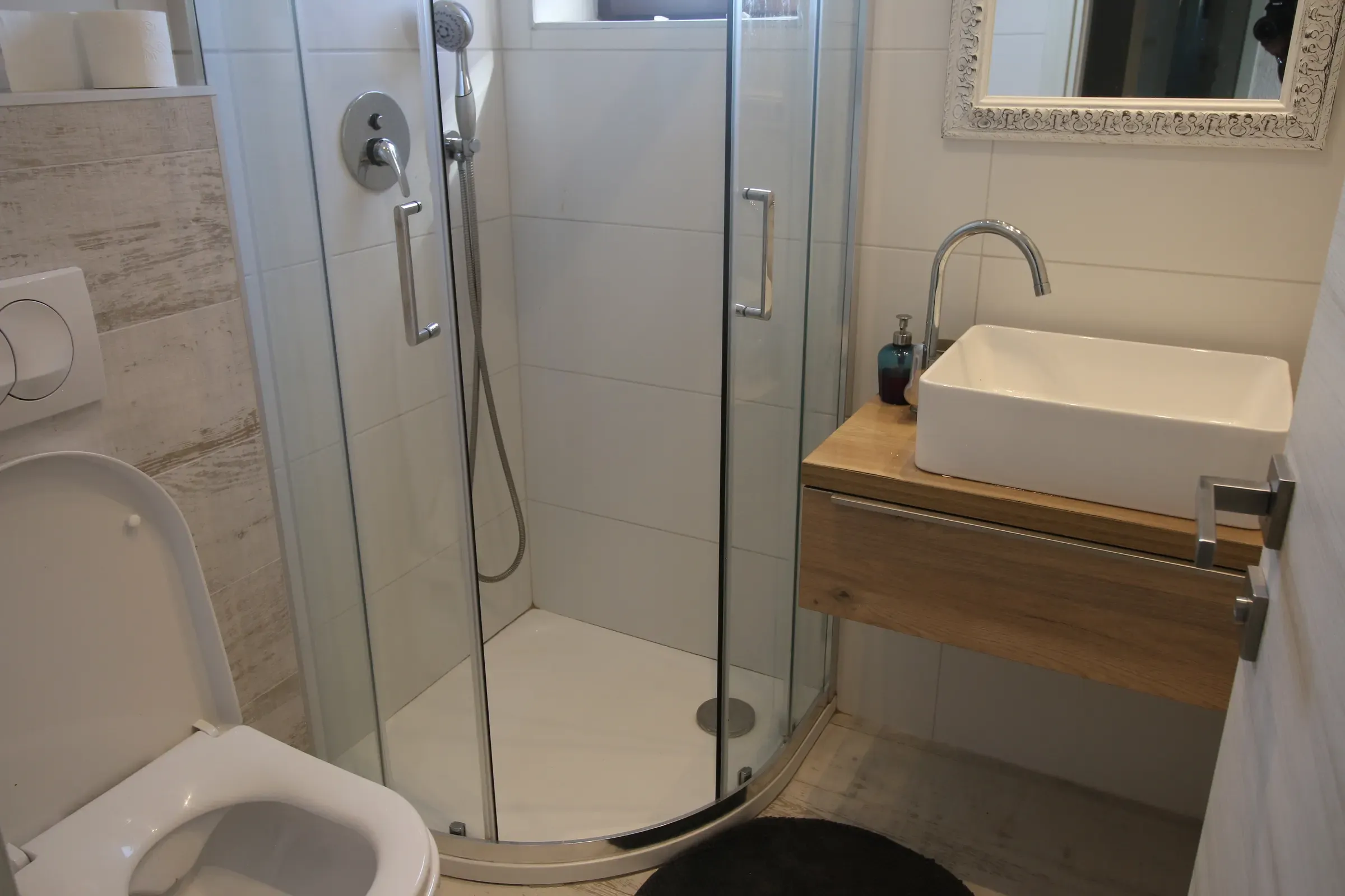 Bathroom with a corner shower and vessel sink on a wooden vanity