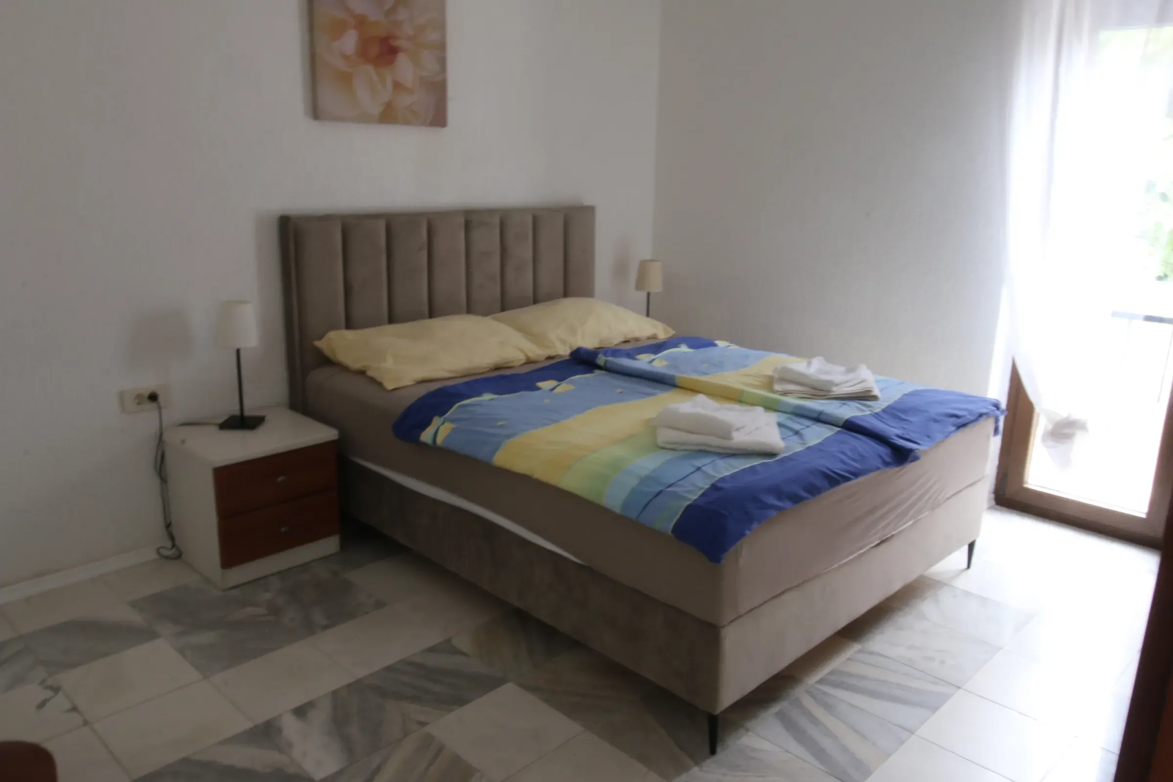 Bright double bedroom with striped bedding beside the terrace