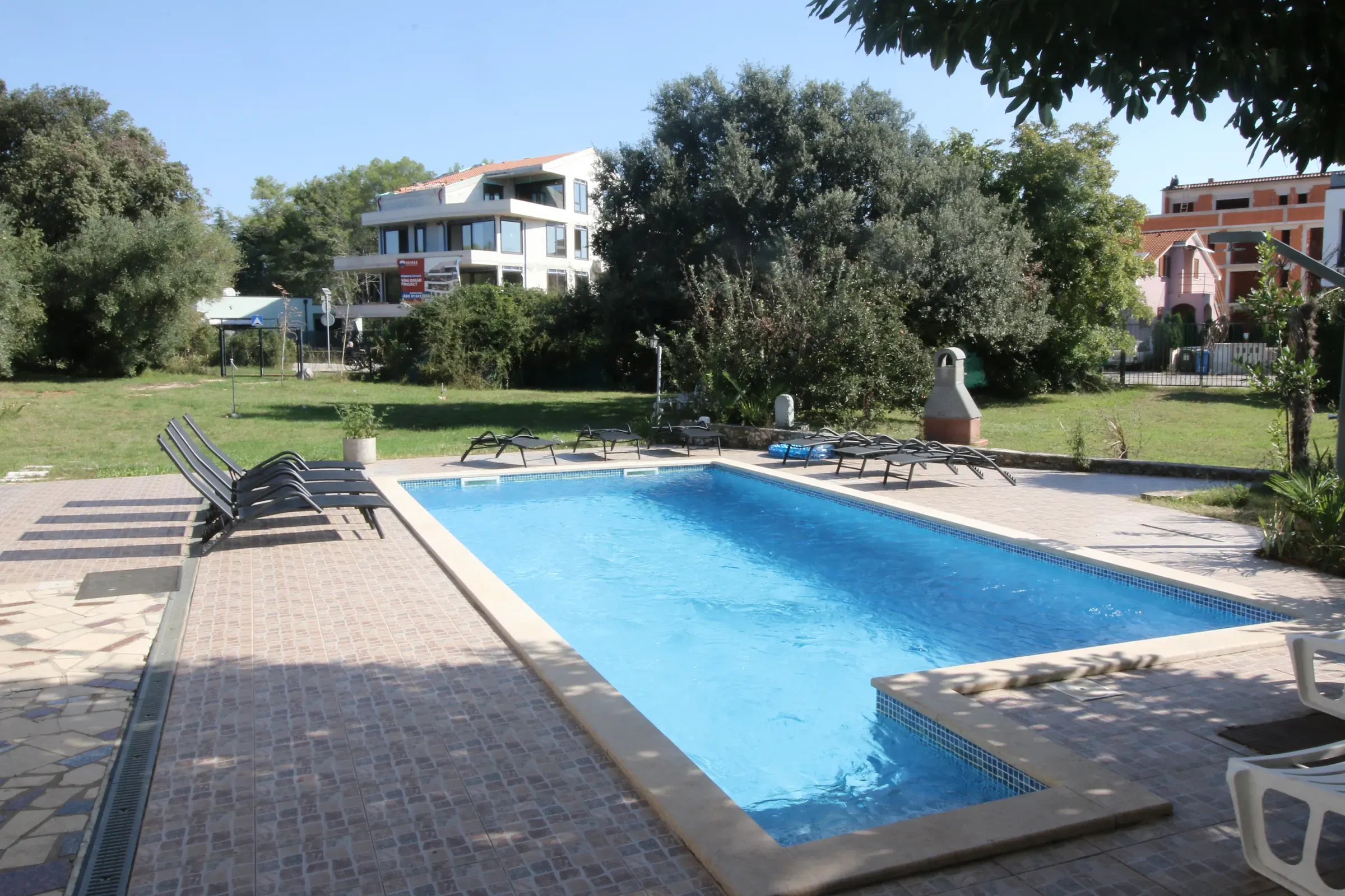 The pool and paved sun deck beside the villa’s large garden lawn