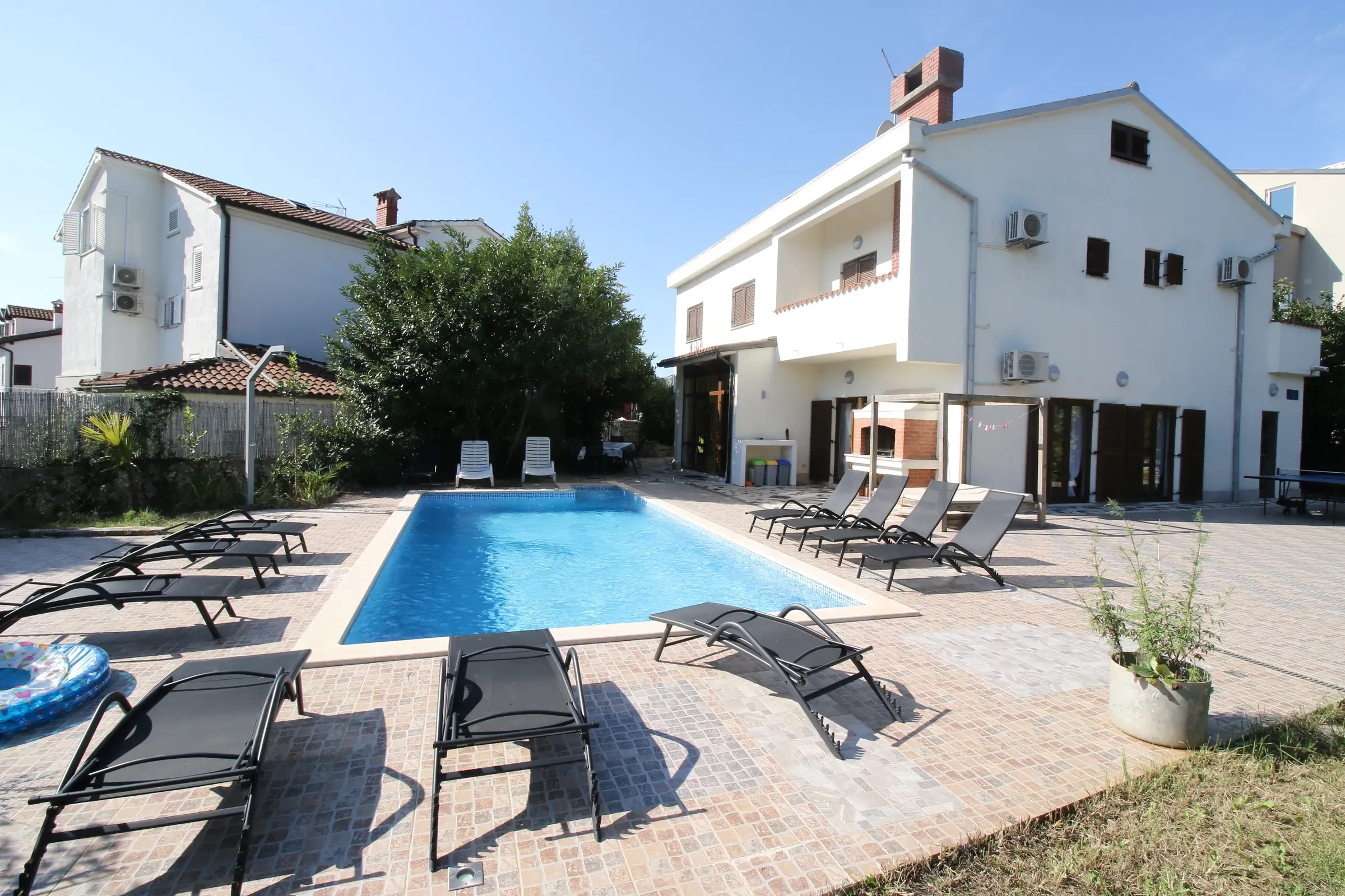 Private pool with sun loungers in front of the white Villa Eucalyptus on a sunny day