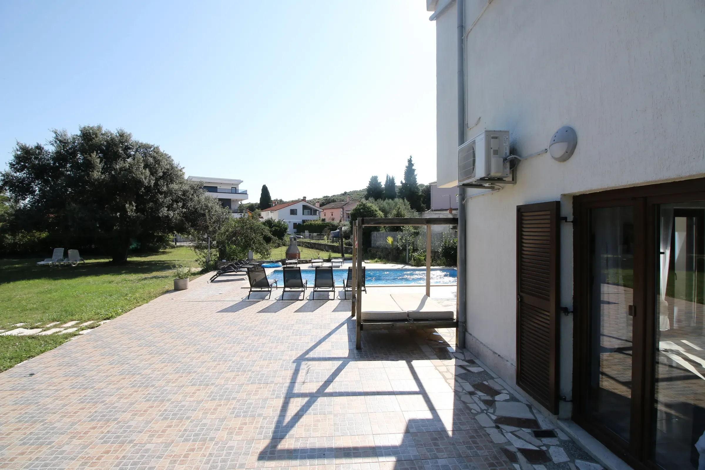 Paved terrace opening onto the garden and pool deck