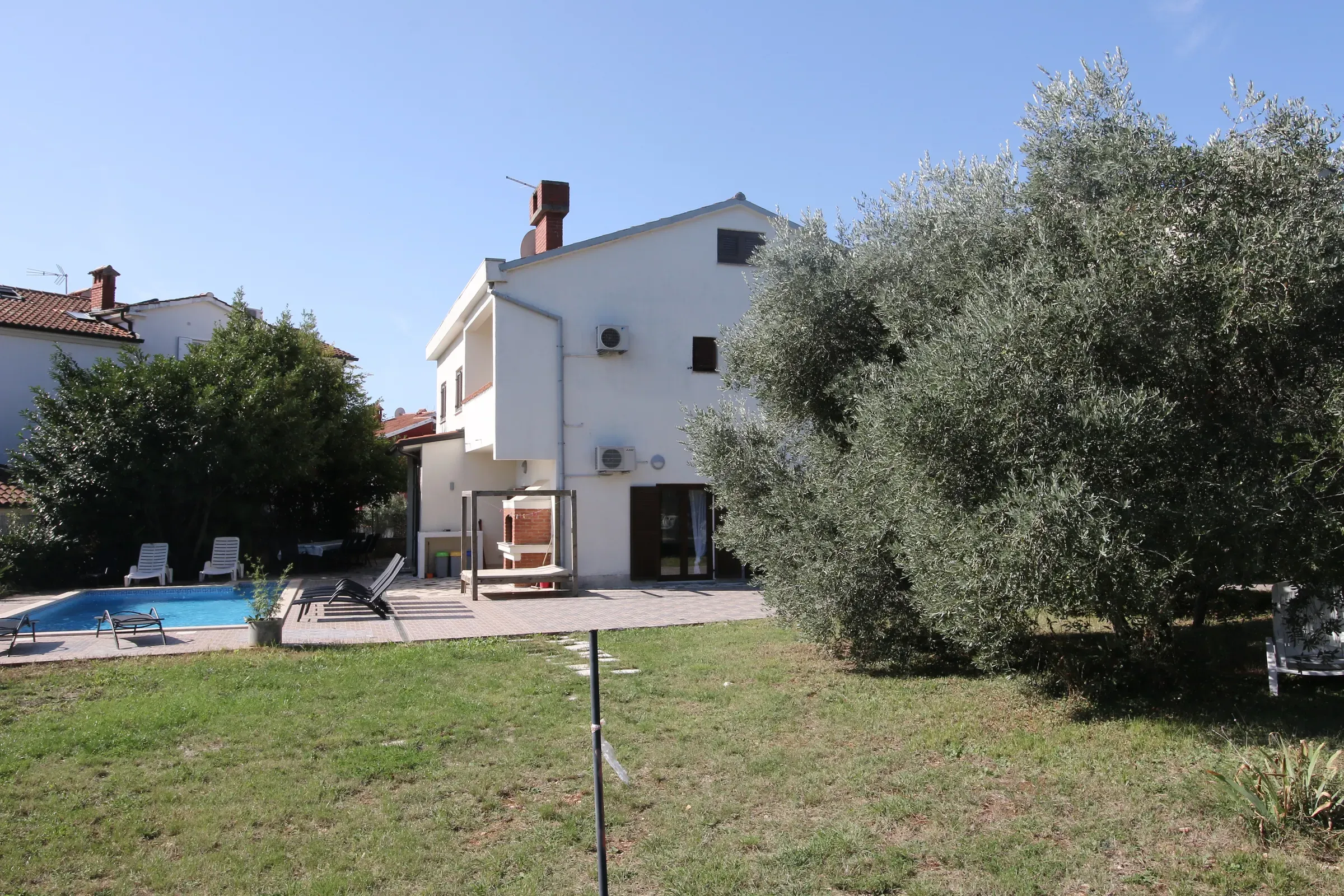 The white villa rising behind mature olive trees in the garden