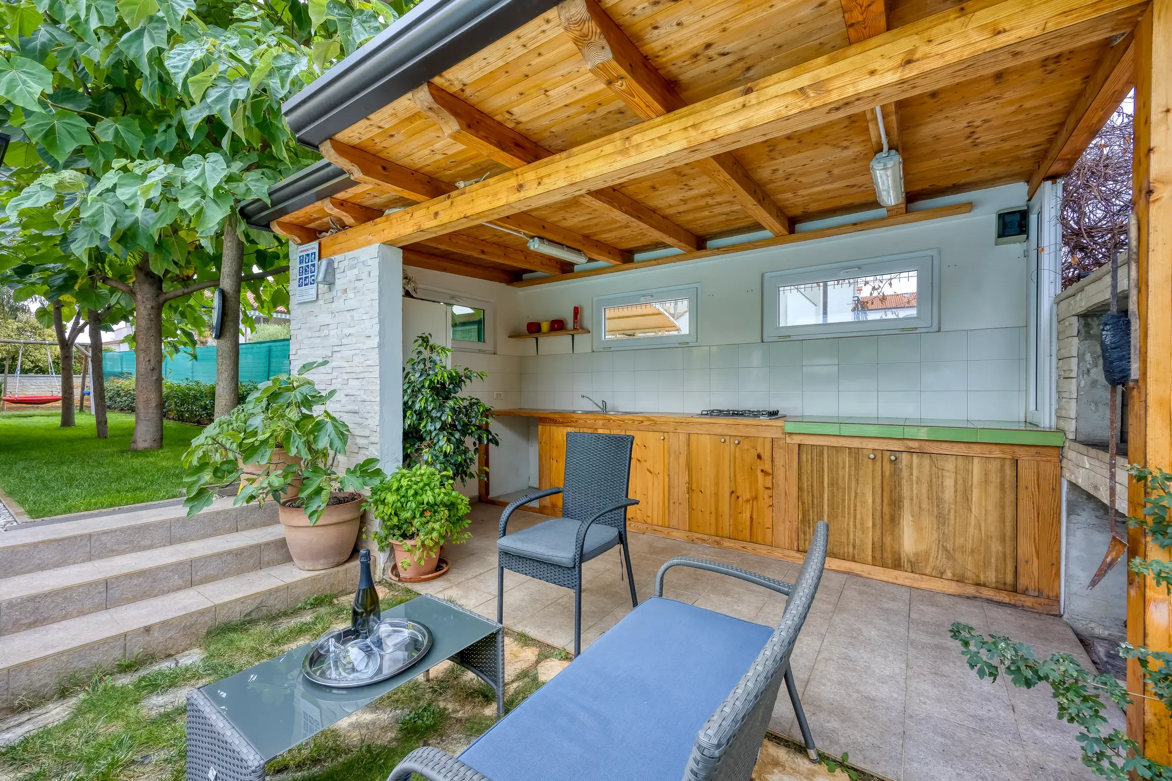 Outdoor kitchen and lounge seating under the timber pergola