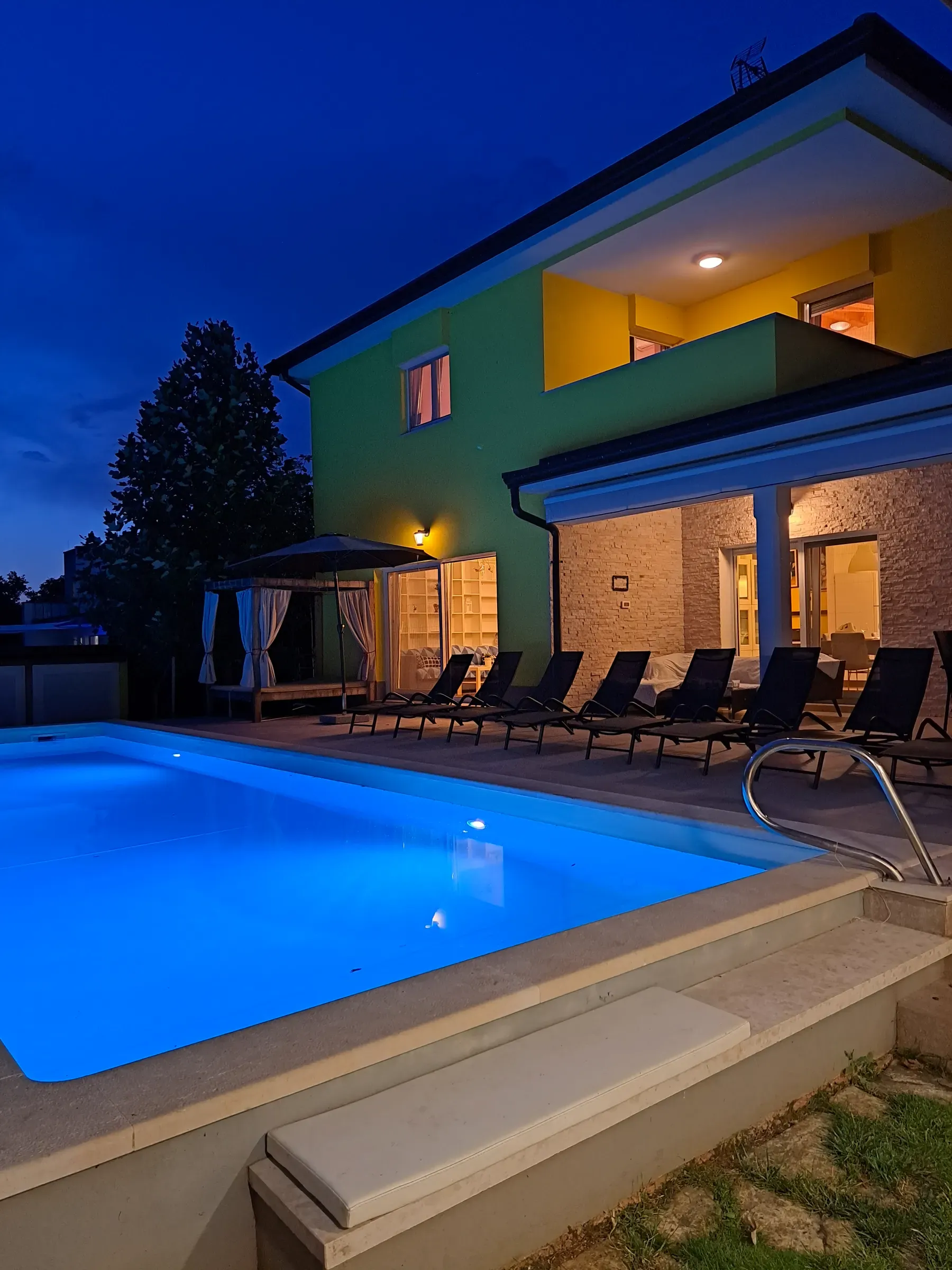 The pool glowing blue against Villa Gaya at nightfall