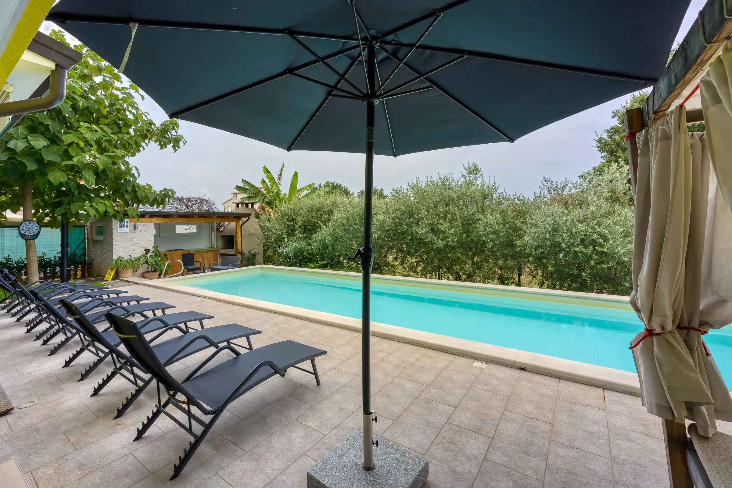 Parasol-shaded loungers on the pool deck of Villa Gaya