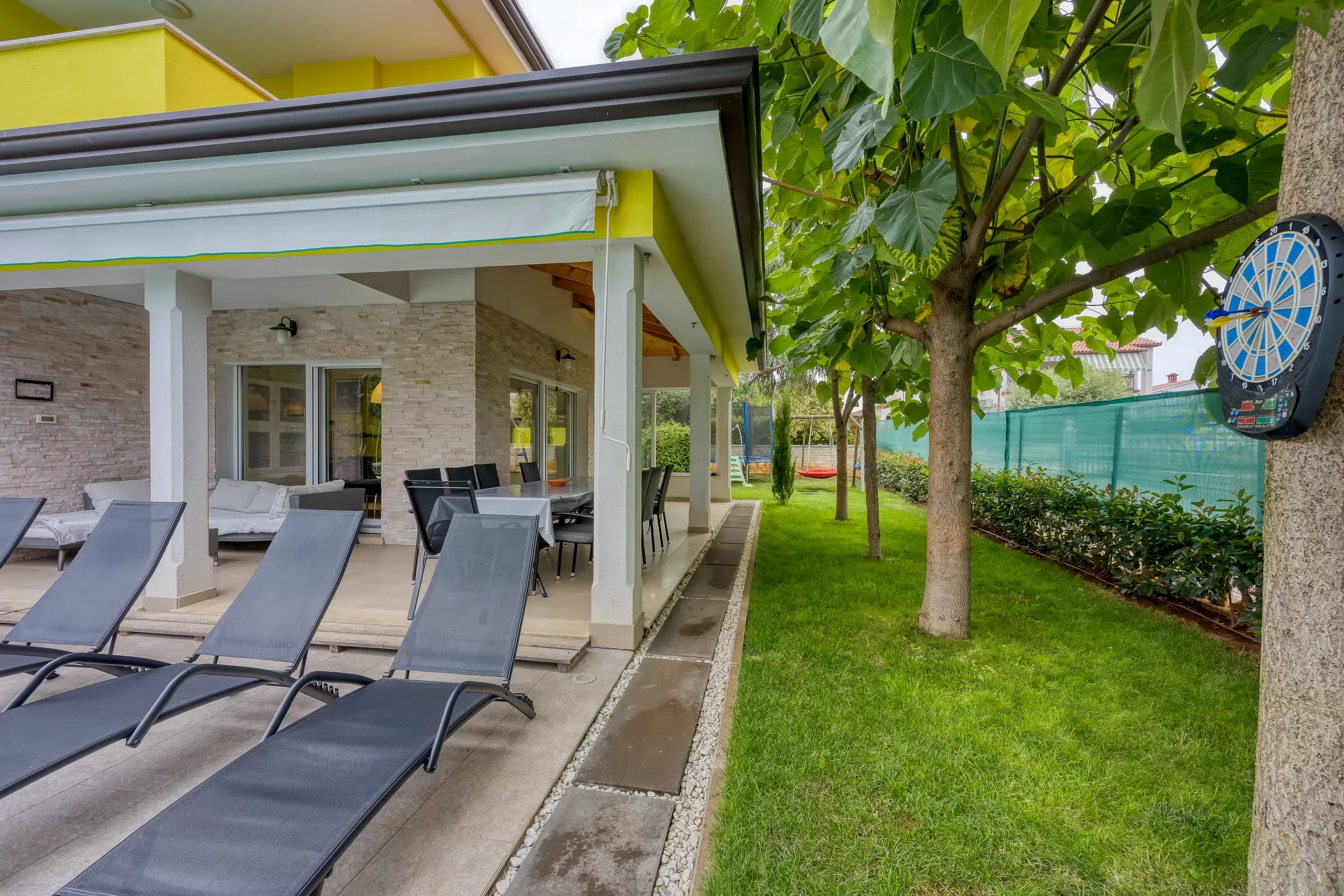 Sun loungers along the villa terrace beside the garden